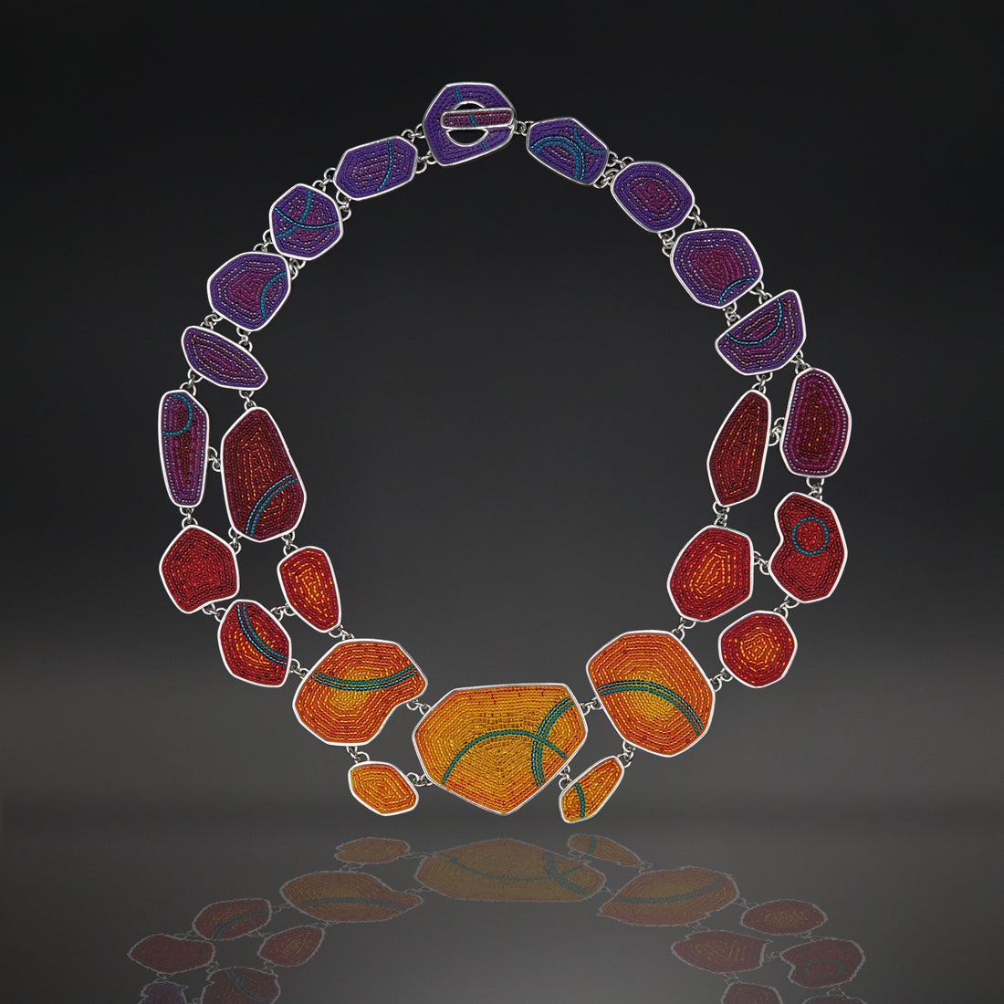 Micro-mosaic necklace made up of a variety of shapes, like pebbles, with a toggle clasp. In warm shades from yellow to plum.