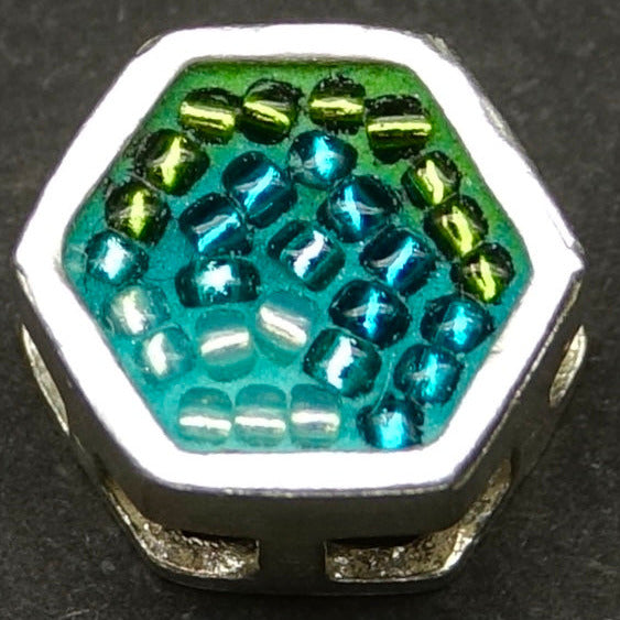 Hexagonal bead with green and blue pattern on a black background