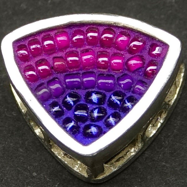 Triangular jewelry piece with fuschia purple and dark blue ombre pattern on a dark gray background